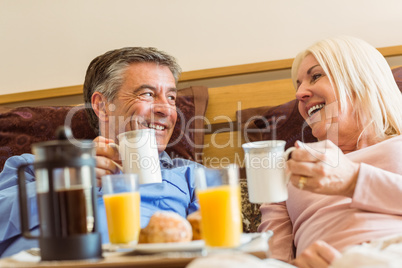 Happy mature couple having breakfast in bed