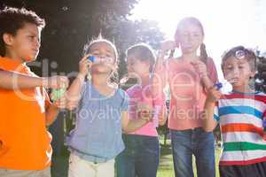 Little friends blowing bubbles in park