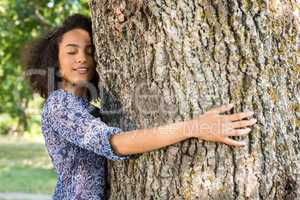 Pretty young woman hugging a tree