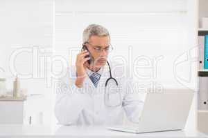 Doctor phoning and using computer