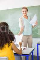 Female teacher handing paper to student