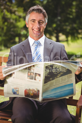 Businessman reading newspaper in the park