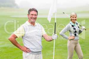 Happy golfer holding flag for cheering partner