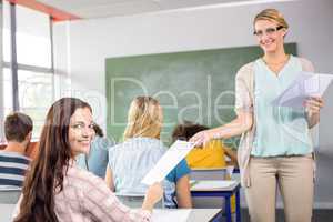 Teacher handing paper to student in class