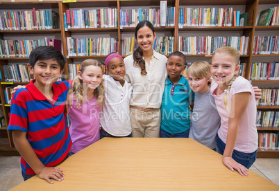 Cute pupils smiling at camera in library