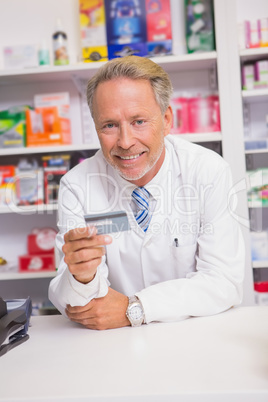 Smiling senior pharmacist holding credit card