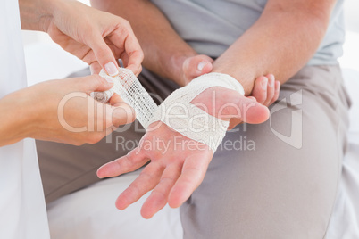 Doctor bandaging her patient hand