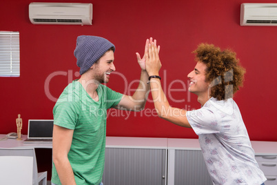 Casual young businessmen high fiving in office
