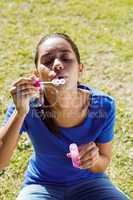 Pretty woman blowing bubbles in the park