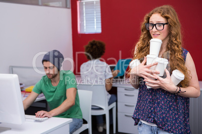 Casual businesswoman carrying disposables glasses in office