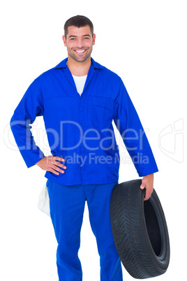 Smiling male mechanic holding tire