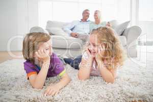 Siblings looking at each other while parents sitting on sofa