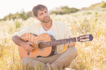 Happy man smiling and playing guitar