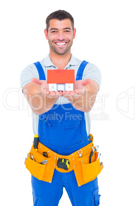 Portrait of happy construction worker holding house model