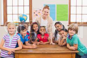 Cute pupils and teacher smiling at camera in classroom