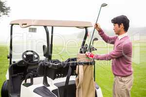 Golfer taking club in golf bag