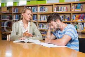 Student getting help from tutor in library