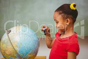 Girl looking at globe through magnifying glass