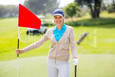 Female golfer smiling at camera and holding her golf club