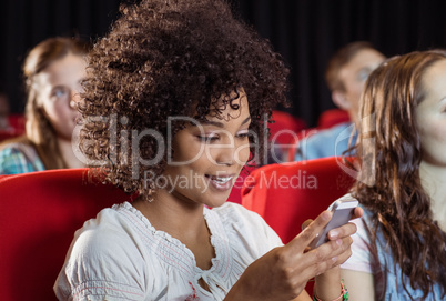 Woman text messaging on her mobile during movie Woman text messaging on her mobile during movie