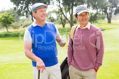 Golfing friends smiling and holding clubs