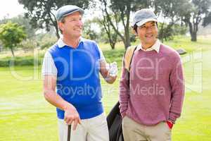 Golfing friends smiling and holding clubs