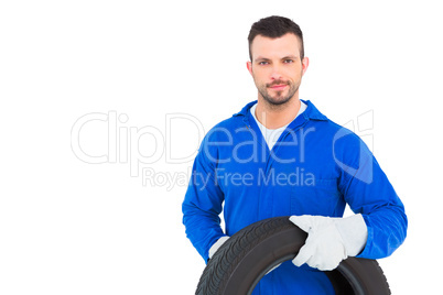 Smiling male mechanic holding tire