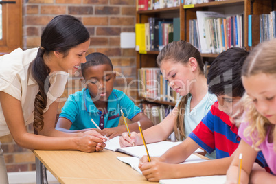 Pretty teacher helping pupils in library