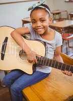 Little girl playing guitar in classroom