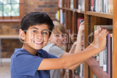 Cute pupils looking for books in library