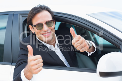 Happy driving businessman with thumbs up
