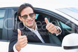 Happy driving businessman with thumbs up