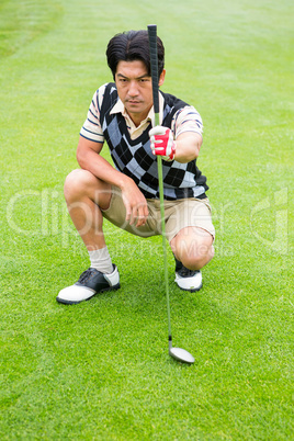 Crouching golfer holding club looking away