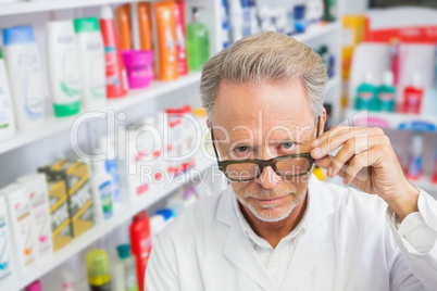 Serious pharmacist holding his glasses