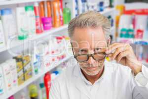 Serious pharmacist holding his glasses