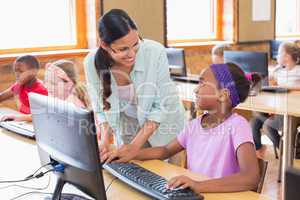 Cute pupil in computer class with teacher