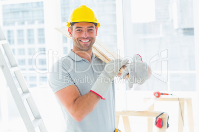 Manual worker carrying planks in building