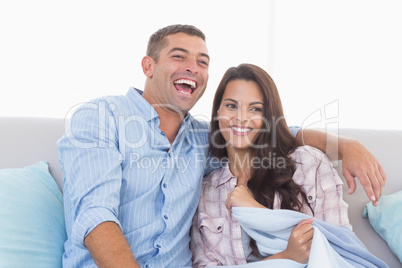 Happy couple watching TV on sofa