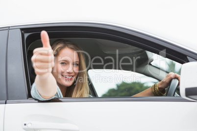 Happy woman sitting in drivers seat thumb up