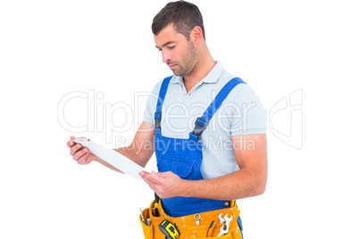 Male carpenter in overalls reading clipboard