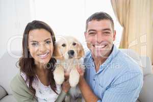 Happy couple holding puppy at home