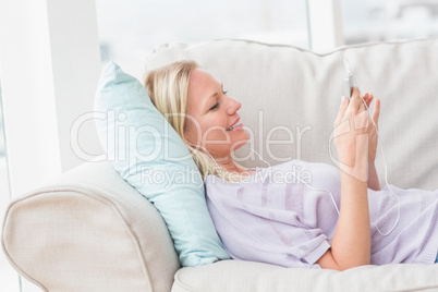 Woman listening music while lying on sofa