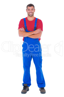 Handyman in overalls standing arms crossed over white backgound