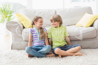 Siblings looking at each other while sitting in liviung room