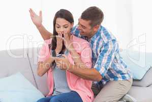 Man gifting ring to surprised woman on sofa
