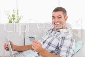 Happy man shopping online through laptop using credit card