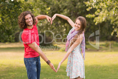 Cute couple in the park making heart shape