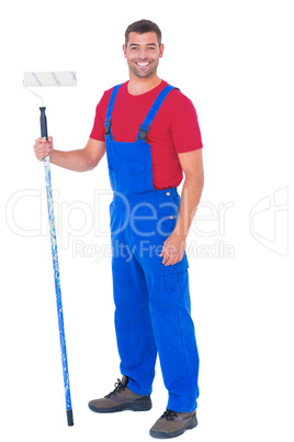 Handyman in overalls holding paint roller on white background