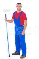 Handyman in overalls holding paint roller on white background