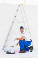 Handyman in overalls opening paint can at home